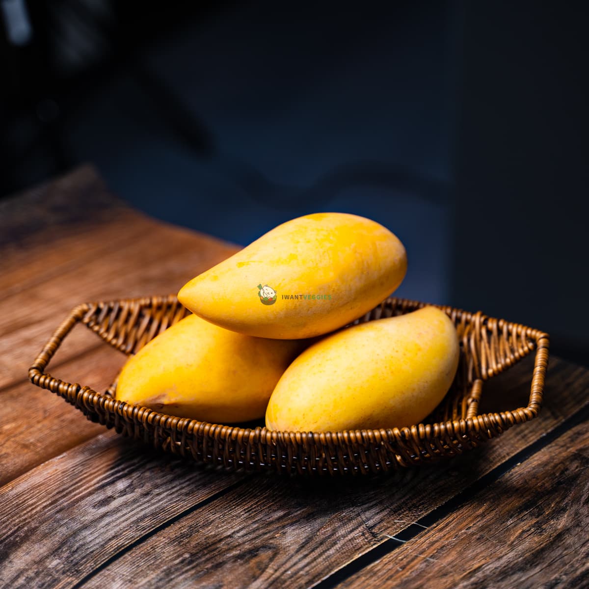 3 Thai mangoes in basket on wooden surface. Sweet, juicy and ripe. Tropical fruits.