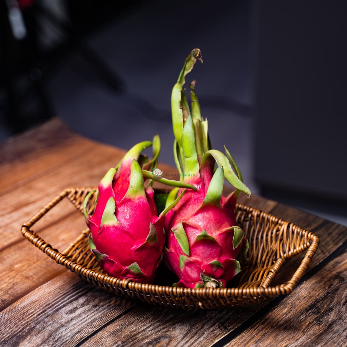 Two red dragon fruits on a basket and wooden surface. Colorful, ripe, and ready-to-eat tropical fruits.