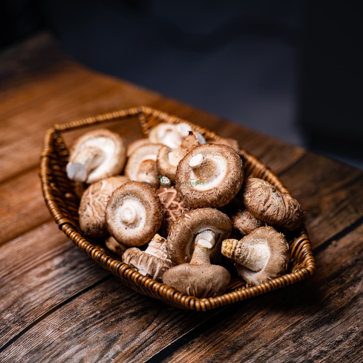 Basket of shiitake mushrooms on wood surface - brown caps, white stems. Fresh, earthy, and nutritious.
