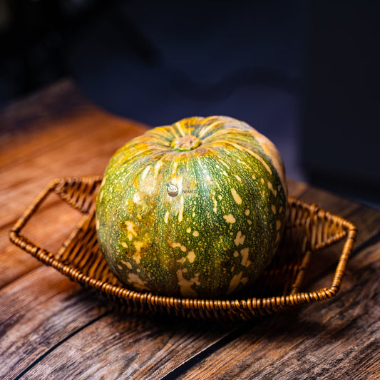 green pumpkin with orange spots on a wooden surface.