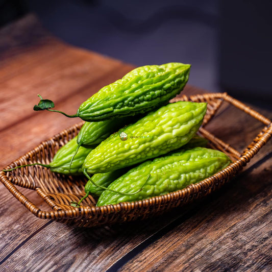 Small green bitter gourds with bumpy skin on a wooden surface