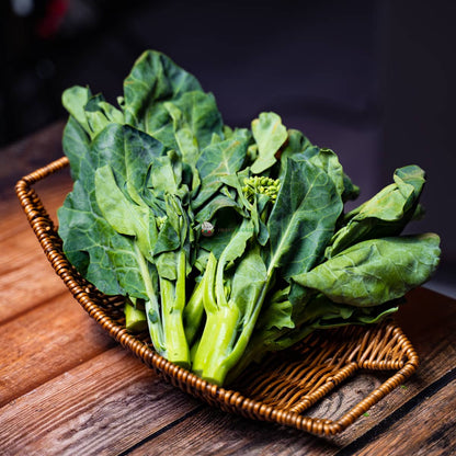 Hong Kong kailan on basket and wood - fresh green leaves with thin stems. Popular Chinese vegetable.
