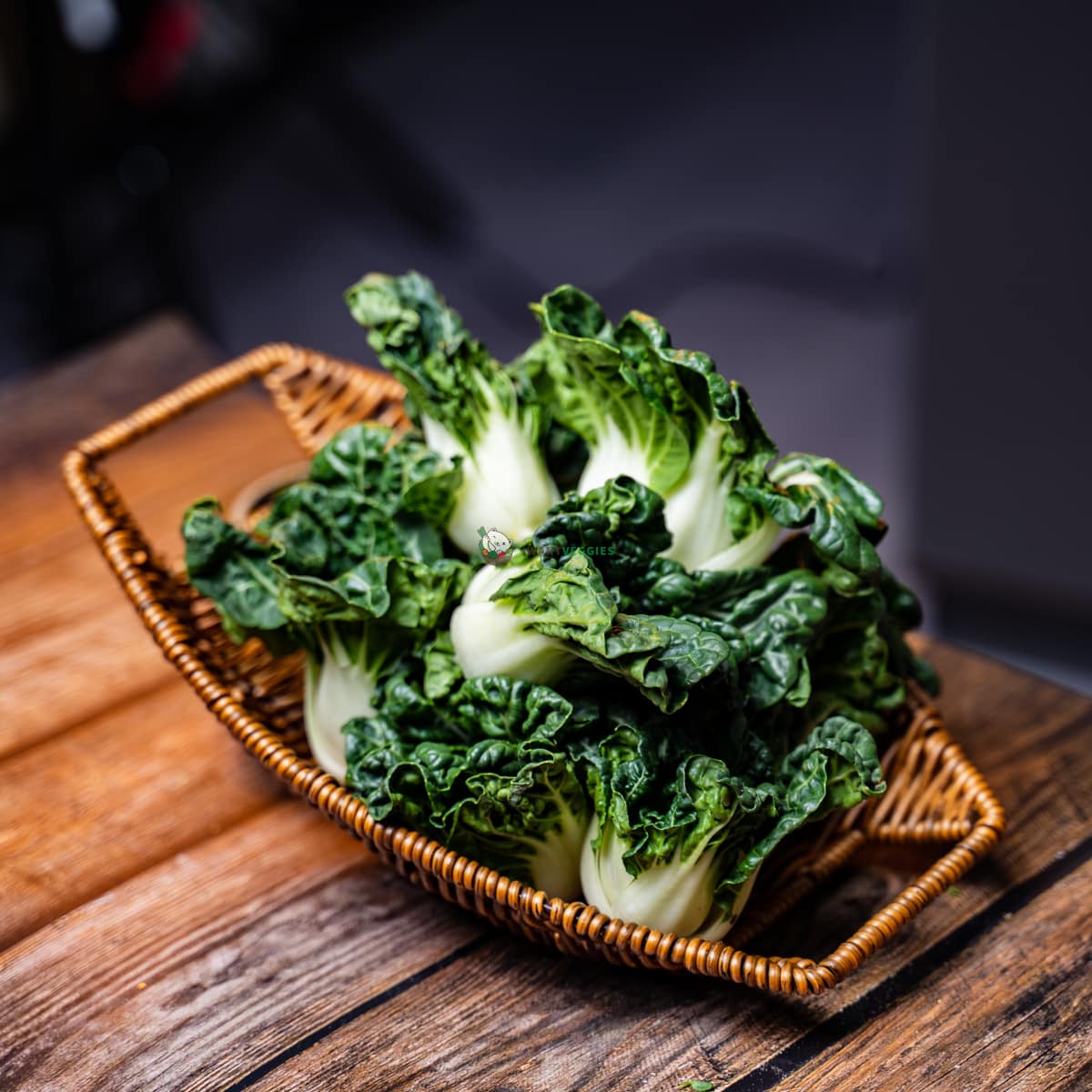 Fresh nai bai or milk cabbage leaves laid on basket and wood surface. A healthy and nutritious green vegetable