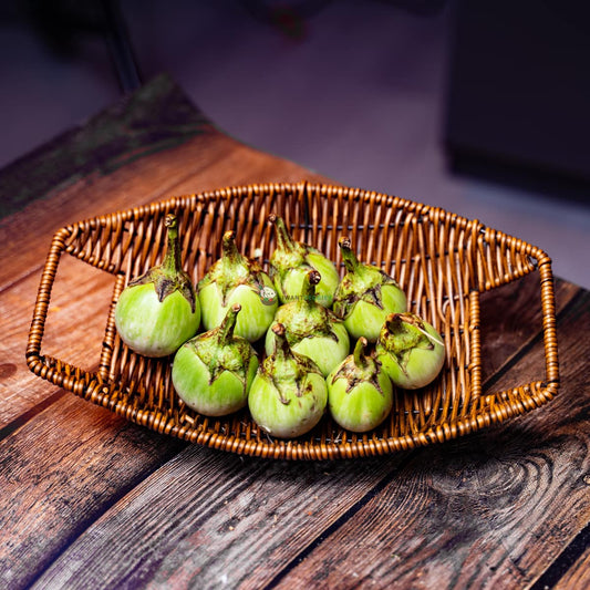 Nine Thai eggplants arranged in rattan basket on wood surface. Small, round, and colorful eggplants native to Thailand