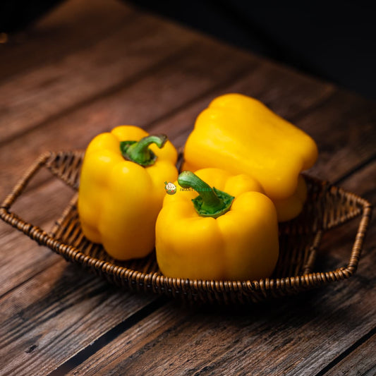 Three bright yellow bell peppers on a basket and wooden surface - fresh, vibrant and healthy.
