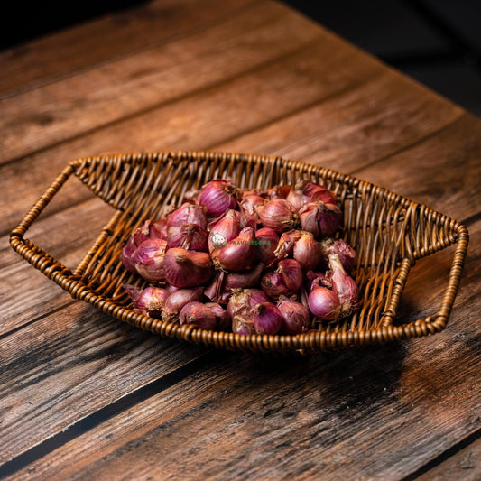 Fresh shallots in a basket on wooden surface. Purple-brown bulbs with long green stems. Local produce for tasty dishes.