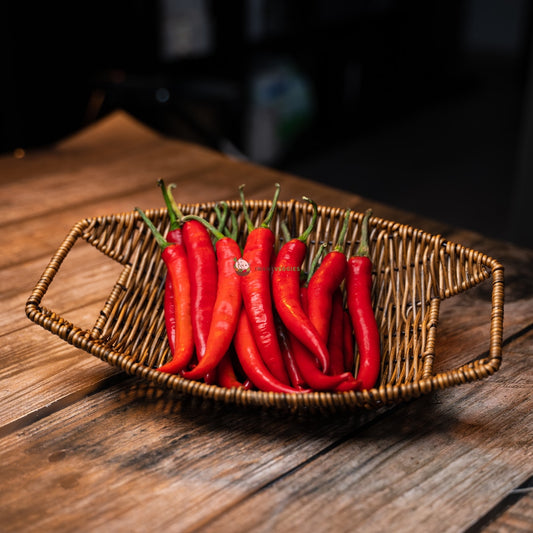Basket of red chillis on wooden surface. Spicy, vibrant and fresh produce.