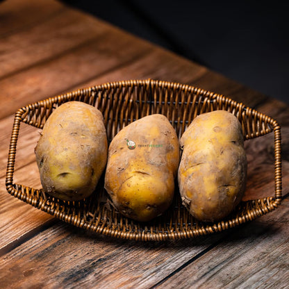 Three fresh potatoes in a basket on wooden surface, with natural texture and earthy colors.