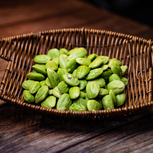 A basket of petai, also known as stink beans, on a wooden surface. The petai are large, green beans with a strong odor.