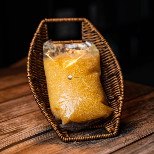 A packet of yellow chopped garlic in water, sitting on a wooden basket. The garlic is fresh and has a strong aroma.