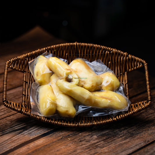 A packet of peeled ginger sits on a wooden basket. The ginger is a light brown color and has a rough, bumpy texture.